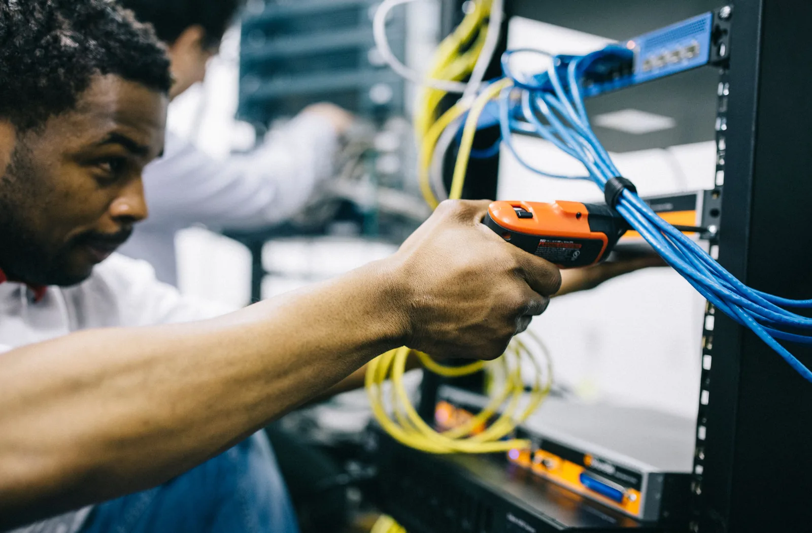 A technician patching network cables into a rack in a small business comms cabinet
