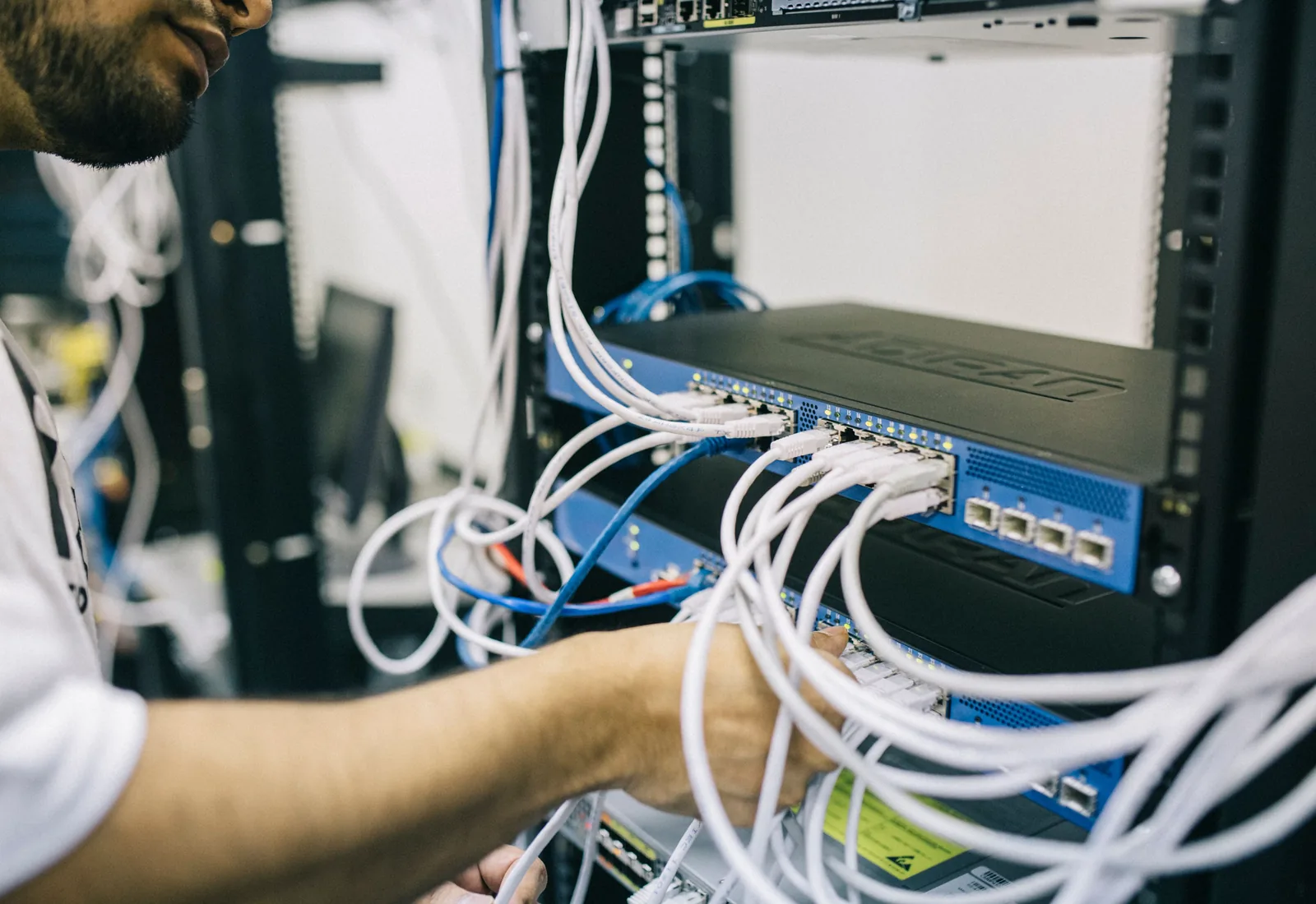 A technician working on network cabling inside a comms rack